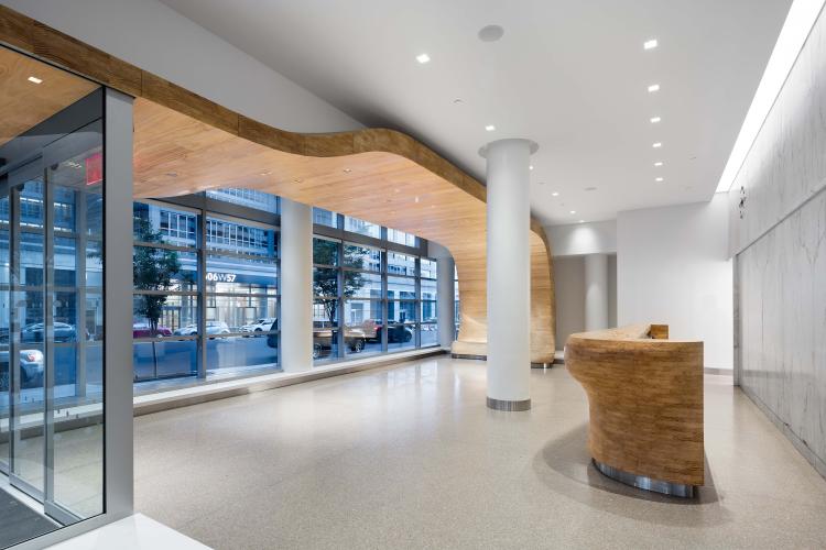 White lobby accented with a light wood front desk and border along a window spanning the building's front.