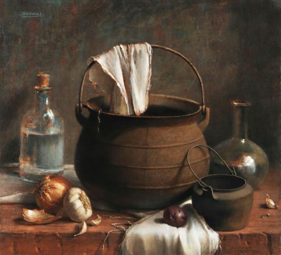A large iron kettle surrounded by a smaller iron pot, an onion, a bulb of garlic, and two bottles of water on a wooden table top.