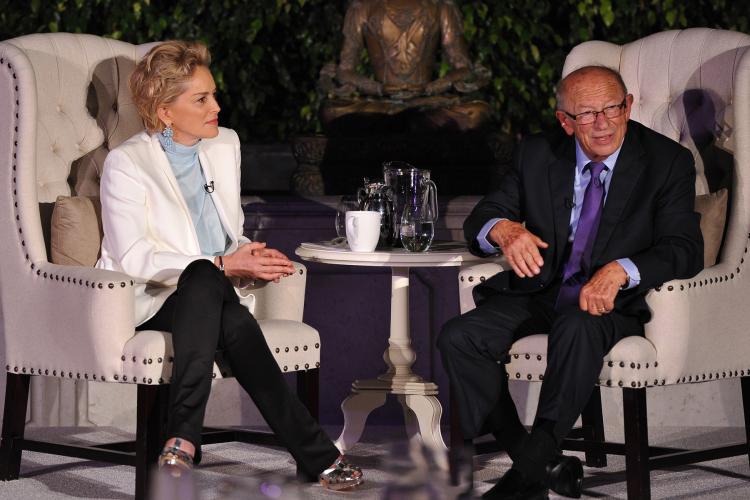 A man and woman talk while sitting in wingback chairs.