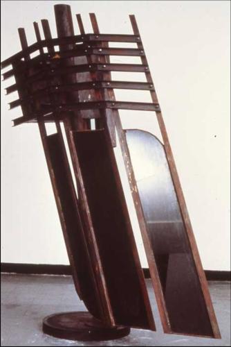 A freestanding, dark-colored sculpture made of steel and glass.
