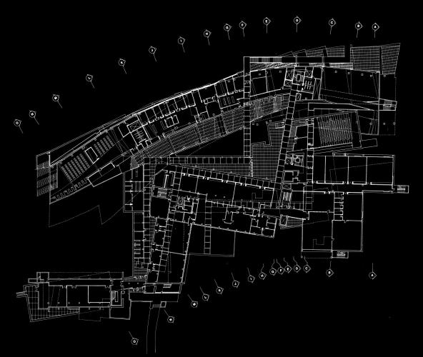 Outline drawing of a building complex in white set against a black background.