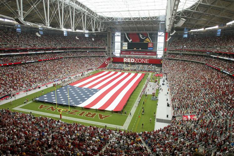 Interior view of a stadium filled with a crowd and an American flag spread across the playing field.