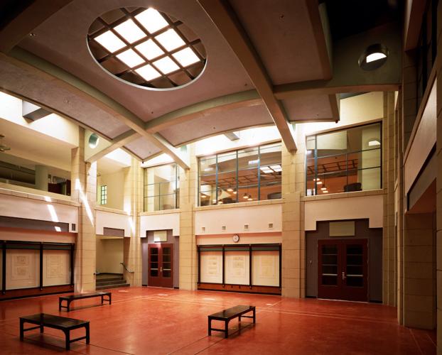 An arched drop ceiling with a skylight window covers a spacious room, empty except for three benches.