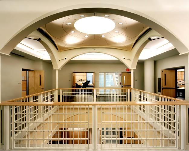 A concave drop ceiling with recessed lights illuminates a space open to the lower floor. 