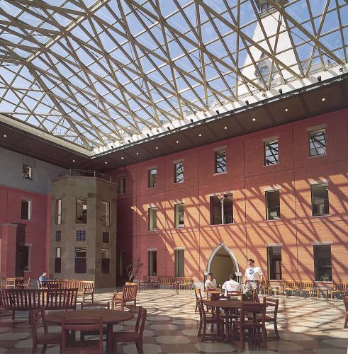 A glass roof covers an atrium with tables and benches for gathering and studying.