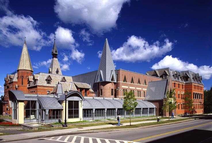 Exterior view of a large building with two types of brick facades and three spires.