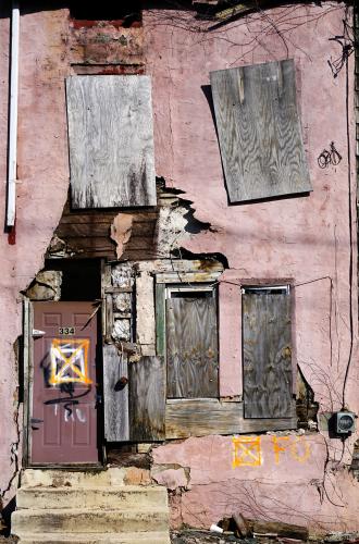 A worn-down residential exterior with a deteriorating pink facade.