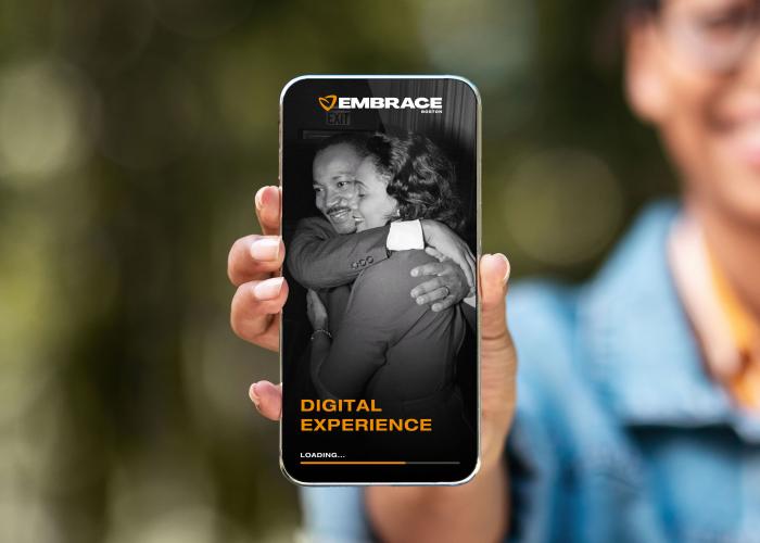 A woman in the background holds up a smartphone showing a photo of Martin Luther King Jr embracing his wife, Coretta Scott King